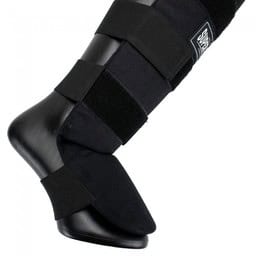 Een close-up van de Super Pro scheenbeschermer Savior in zwart, bevestigd om een beenmodel. De stevige klittenbandsluitingen zorgen voor optimale pasvorm en stabiliteit tijdens het kickboksen. Ontworpen voor maximale bescherming en comfort.