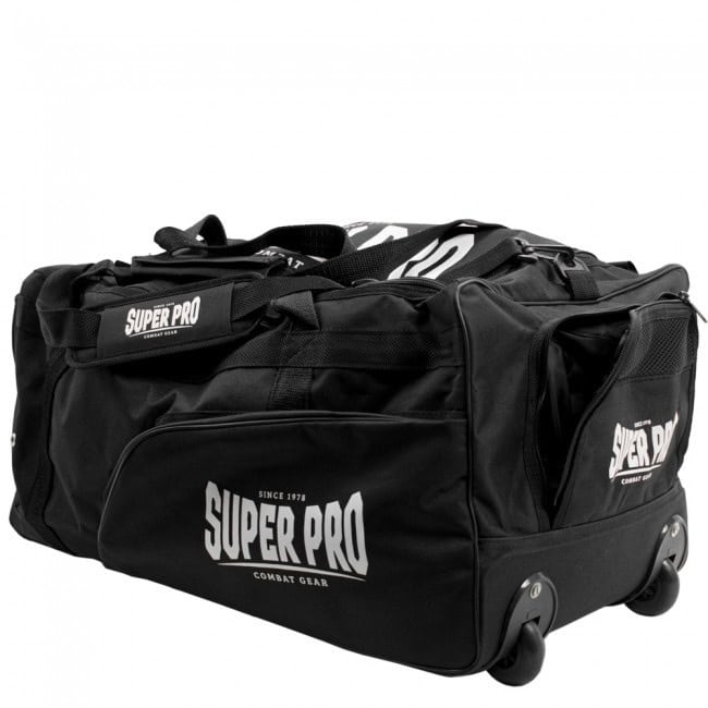 Een schuine opname van een zwarte Super Pro sporttas, waarbij de trolley functie goed zichtbaar is. Aan de onderkant zijn twee stevige wielen gemonteerd. Het grote Super Pro Combat Gear logo is duidelijk op de zijkant van de tas te zien.
