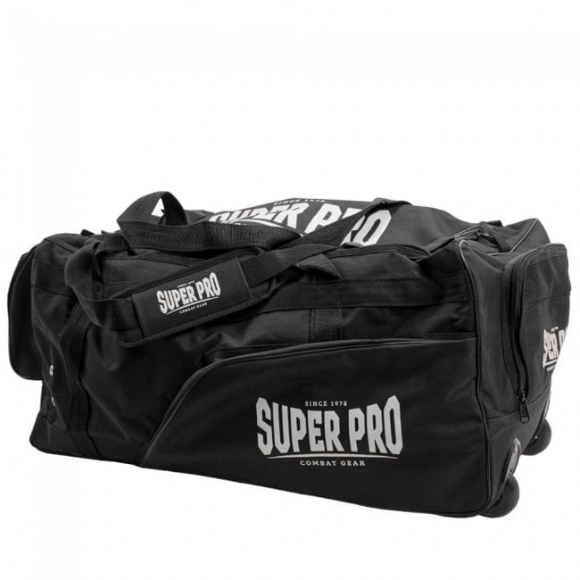 Een brede, licht schuine opname van een grote zwarte sporttas van Super Pro Combat Gear. Het logo is duidelijk zichtbaar op de zijkant en op de schouderriem. De tas is uitgerust met wielen aan de onderkant, wat de functionaliteit als trolley bevestigt.