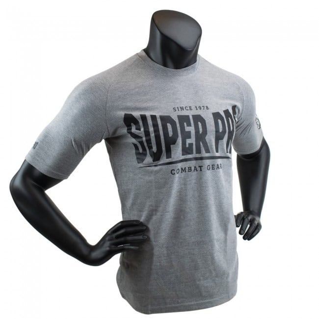Super Pro T-shirt Grijs Schuin toont het shirt vanuit een licht hoekige vooraanzicht. De zwarte opdruk 'Super Pro Combat Gear' springt in het oog op de lichtgrijze stof. Ideaal voor sporters die stijl willen combineren met comfort tijdens hun training.