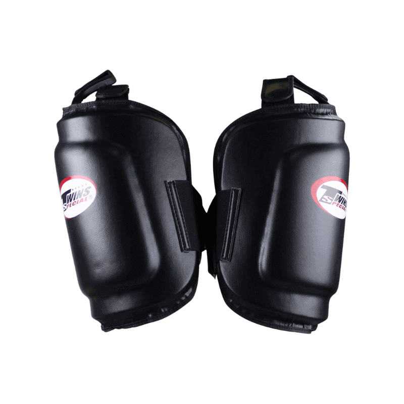 Zwart leren beenbeschermers van Twins Special, met een wit en rood logo op de voorzijde. De stevige padding biedt optimale bescherming tijdens intensieve trainingen.