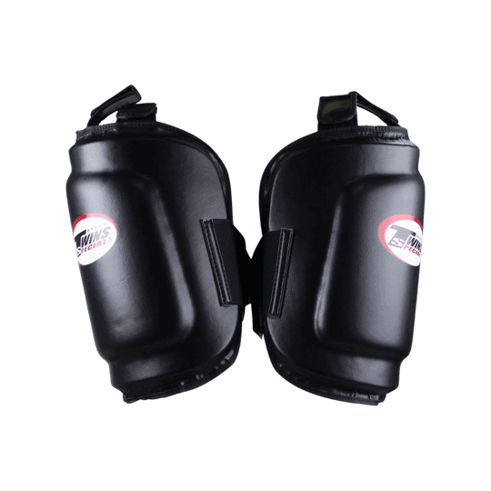 Zwart leren beenbeschermers van Twins Special, met een wit en rood logo op de voorzijde. De stevige padding biedt optimale bescherming tijdens intensieve trainingen.