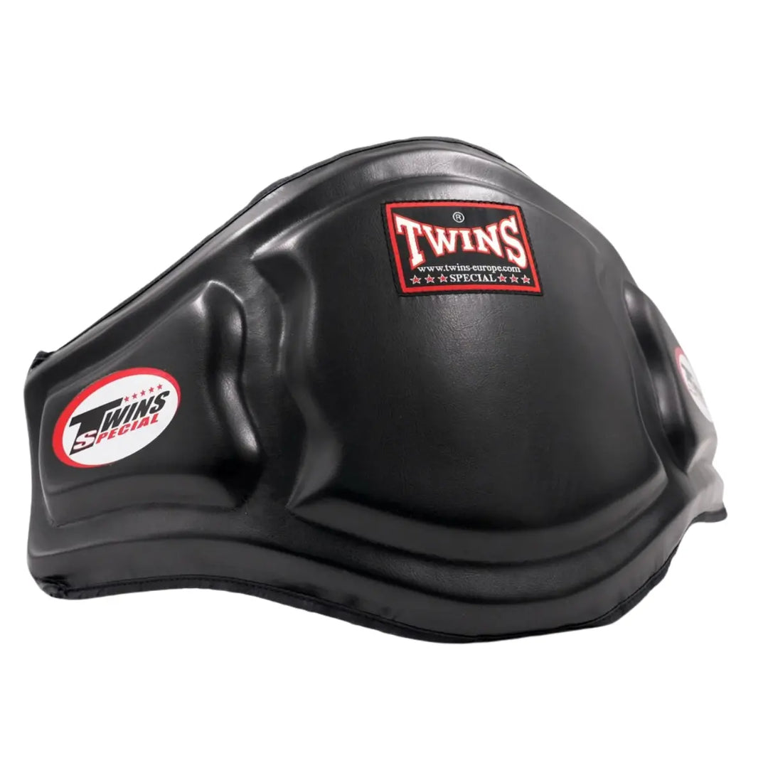 De Twins Bellypad BEPS3 Zwart is gefotografeerd op een witte achtergrond en toont het robuuste, anatomisch gevormde ontwerp. De zwarte leren afwerking straalt kracht en duurzaamheid uit, terwijl het Twins Special-logo op de voorkant de authentieke kwaliteit benadrukt. Deze foto laat duidelijk de bescherming en stevigheid zien die ideaal zijn voor professionele bokstrainingen.