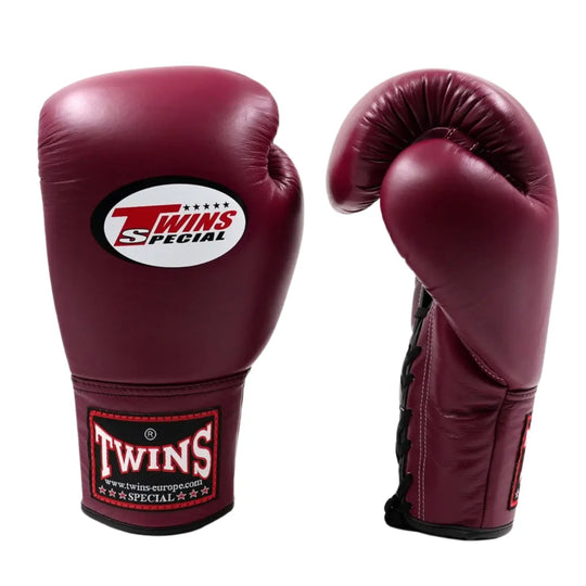 De Twins Bokshandschoenen Maroon BGLL 1 staan rechtop op een witte achtergrond, met één handschoen die de voorkant toont en de andere licht gedraaid is om de pasvorm te laten zien. De diepe maroonkleur en het Twins Special-logo geven de handschoenen een luxe, professionele uitstraling. De stevige vetersluiting en gladde leren afwerking benadrukken de kwaliteit en duurzaamheid van deze premium bokshandschoenen.
