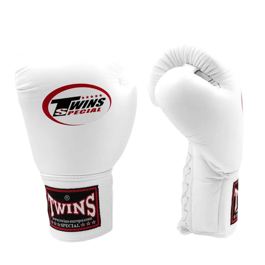 De Twins Bokshandschoenen BGLL 1 Wit staan rechtop naast elkaar op een witte achtergrond. De ene handschoen toont de voorkant met het Twins Special-logo, terwijl de andere de gebogen pasvorm laat zien. De volledig witte leren afwerking met zwarte en rode details straalt klasse en professionaliteit uit, ideaal voor vechters die gaan voor stijl én prestaties.