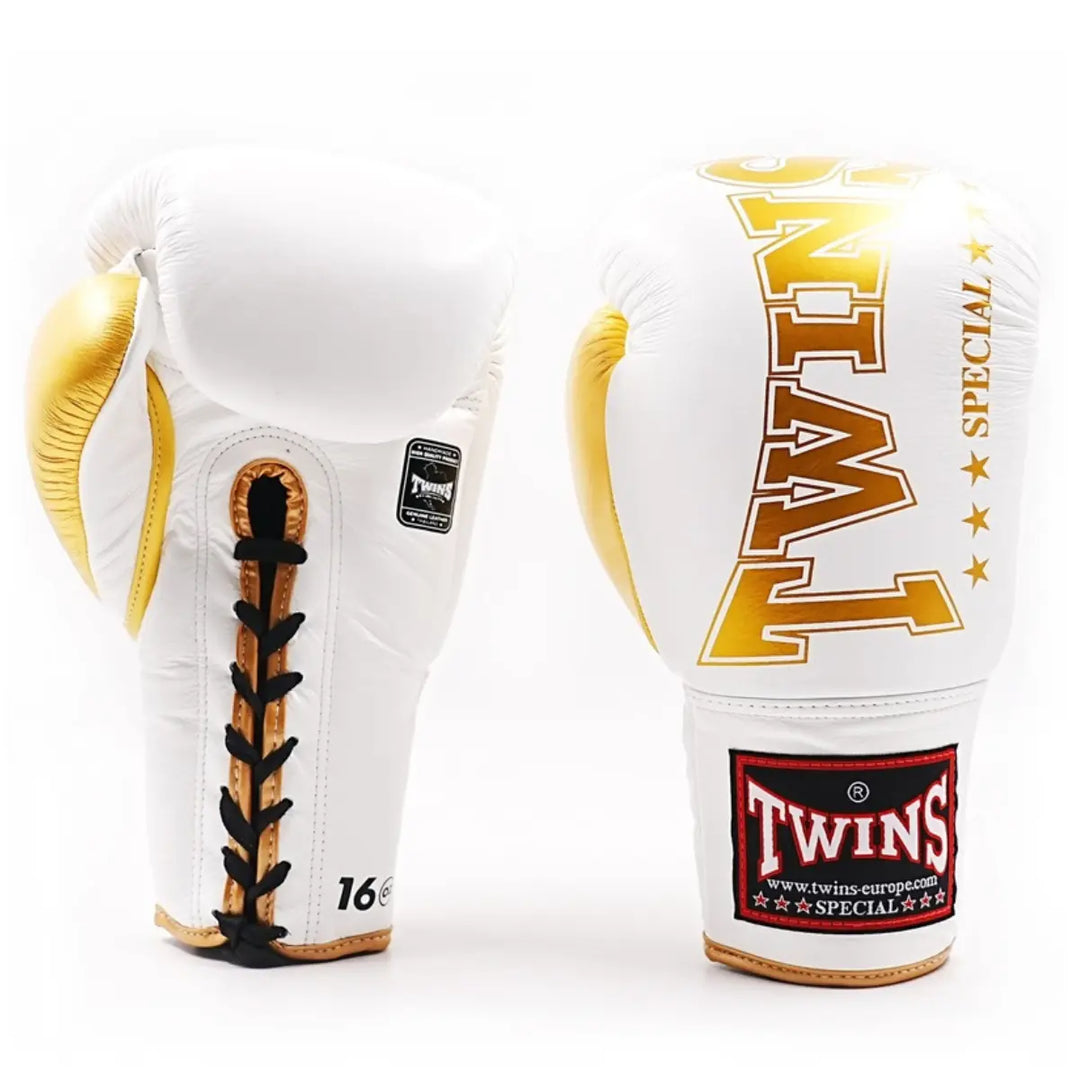 Een paar Twins bokshandschoenen in wit en goud met vetersluiting. De handschoenen tonen het gouden Twins-logo en bieden een luxe afwerking met extra polsstabiliteit, ideaal voor professionele bokssessies en geavanceerde vechters.