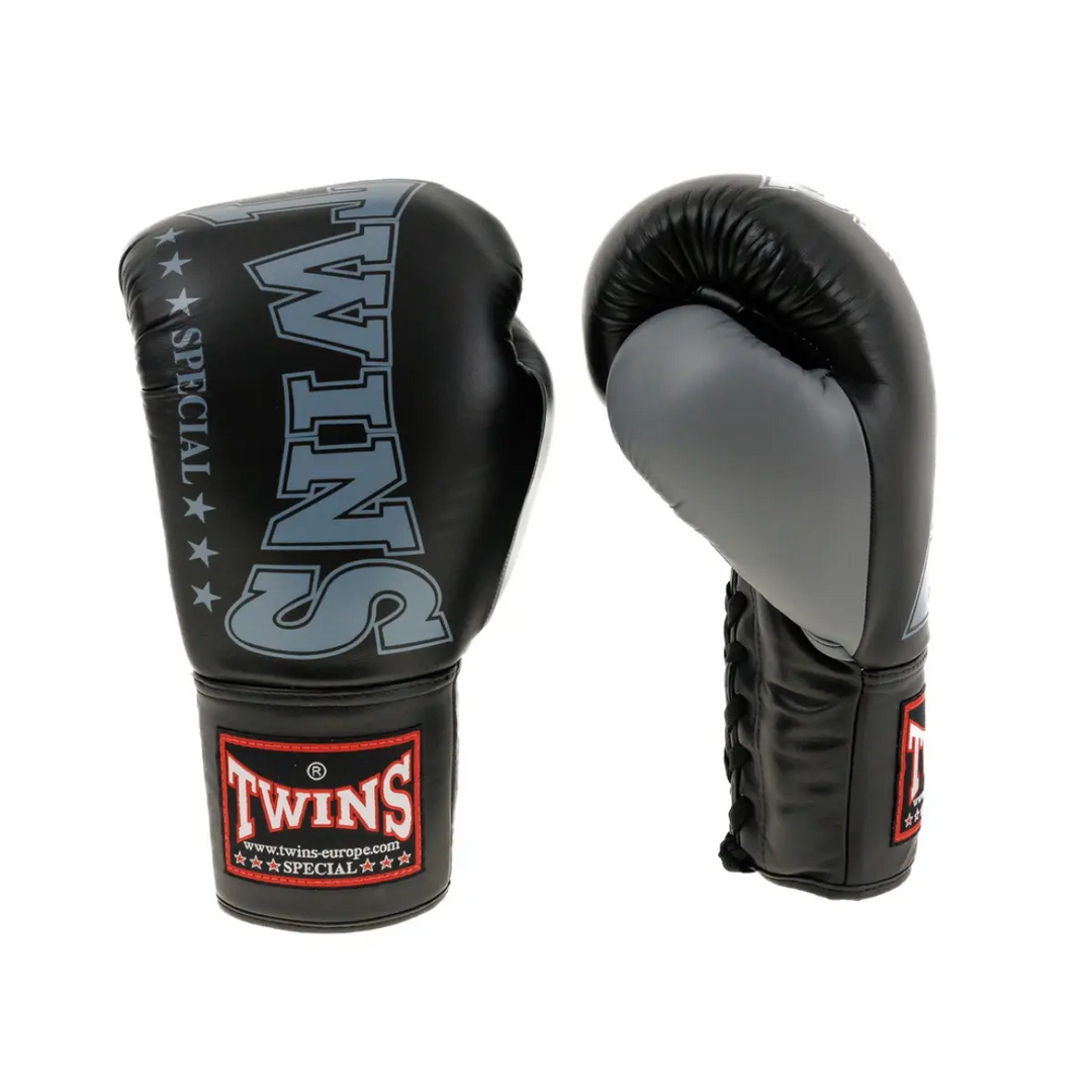 Een paar Twins bokshandschoenen in zwart en grijs, met het herkenbare Twins-logo op de polsband. De handschoenen hebben een glanzende afwerking, vetersluiting en stevige padding, ontworpen voor maximale bescherming en comfort tijdens bokstraining.