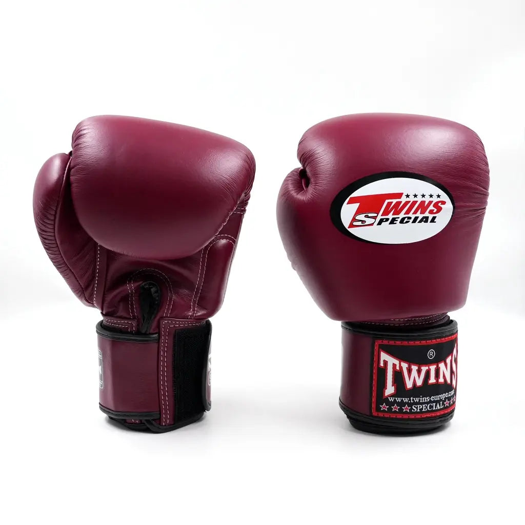 Twee donkerrode Twins bokshandschoenen op witte achtergrond, met wit Twins-logo op de vuistzijde en rood label met zwarte polsband.