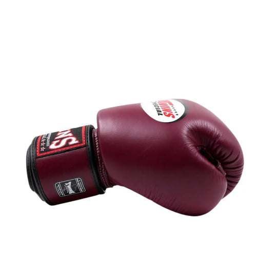 Donkerrode Twins bokshandschoen van leer, liggend op een witte achtergrond met zichtbaar rood Twins-logo op de polsband en wit logo op de bovenzijde.