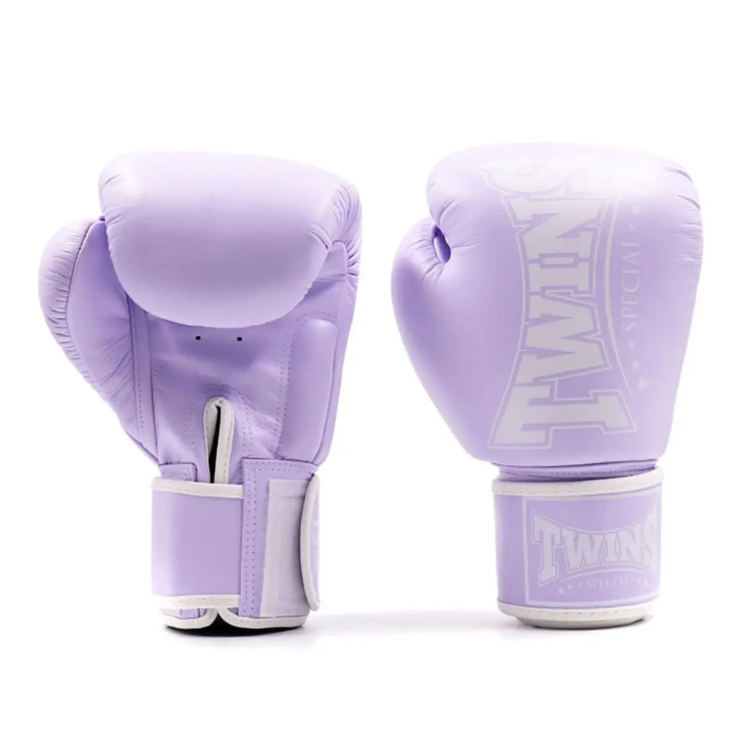 Een paar Twins Bokshandschoenen Paars gemaakt van hoogwaardig leer met stevige klittenbandsluiting. De handschoenen bieden uitstekende polssteun en schokabsorptie, perfect voor intensieve bokstraining en sparring.
