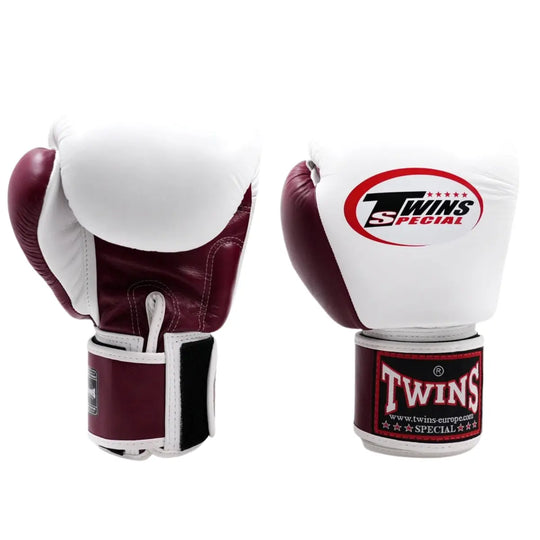Twee Twins bokshandschoenen in bordeauxrood en wit, rechtopstaand op een witte achtergrond met rood Twins-logo op de vuistzijde en rood label op de polsband.