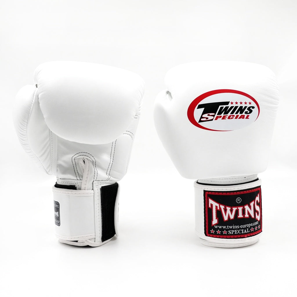 Twee witte Twins bokshandschoenen op witte achtergrond, met rood Twins-logo op de vuistzijde en rood label op de polsband.