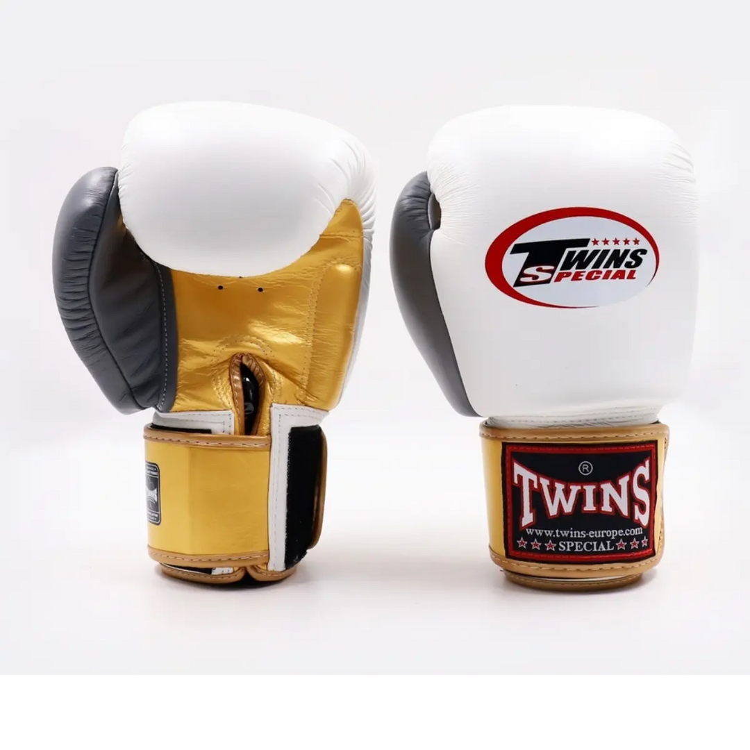 Twee Twins Special bokshandschoenen in wit, goud en zwart leer met klittenbandsluiting en logo-opdruk.
