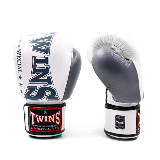 Een paar Twins bokshandschoenen in wit en grijs met zwarte details. De handschoenen tonen het Twins-logo op de polsband en zijn gemaakt van hoogwaardig leer voor duurzaamheid, comfort en optimale bescherming tijdens bokstraining of sparring.