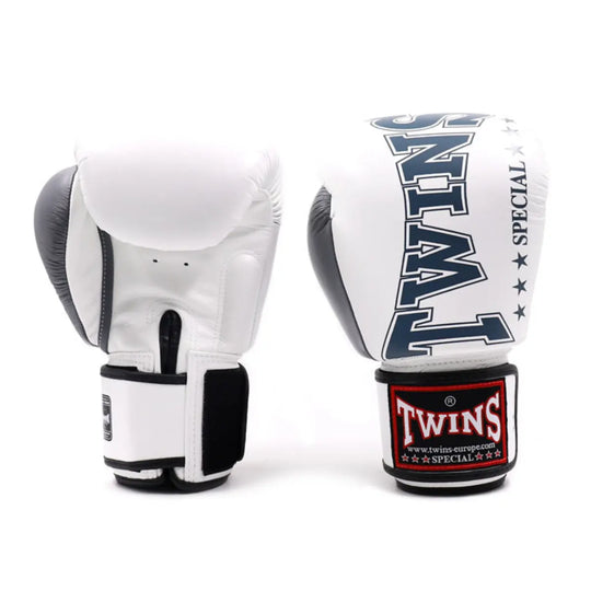 Een paar Twins bokshandschoenen in wit met grijze accenten, staand op een witte achtergrond. De handschoenen tonen het Twins-logo op de polsband en de opdruk “Special” met sterren, en zijn ontworpen voor professionele bokstraining en sparring.