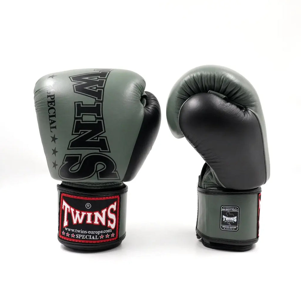 Set groen-zwarte Twins bokshandschoenen op witte achtergrond, rechtopstaand met groot zwart TWINS-logo op de vuistzijde en rood label op de polsband.