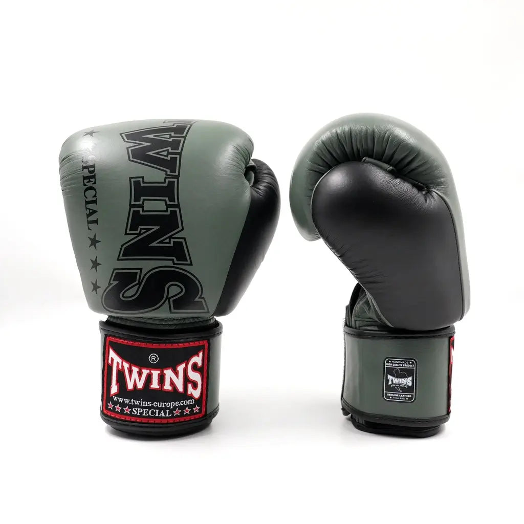 Set groen-zwarte Twins bokshandschoenen op witte achtergrond, rechtopstaand met groot zwart TWINS-logo op de vuistzijde en rood label op de polsband.