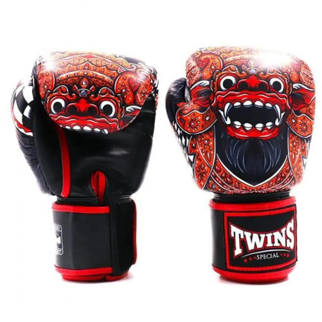Een paar Twins bokshandschoenen in rood met zwart, voorzien van een opvallend Balinees maskermotief. De gedetailleerde illustratie en het Twins-logo op de polsband geven de handschoenen een krachtige, traditionele uitstraling, perfect voor intensieve bokstrainingen en sparringssessies.
