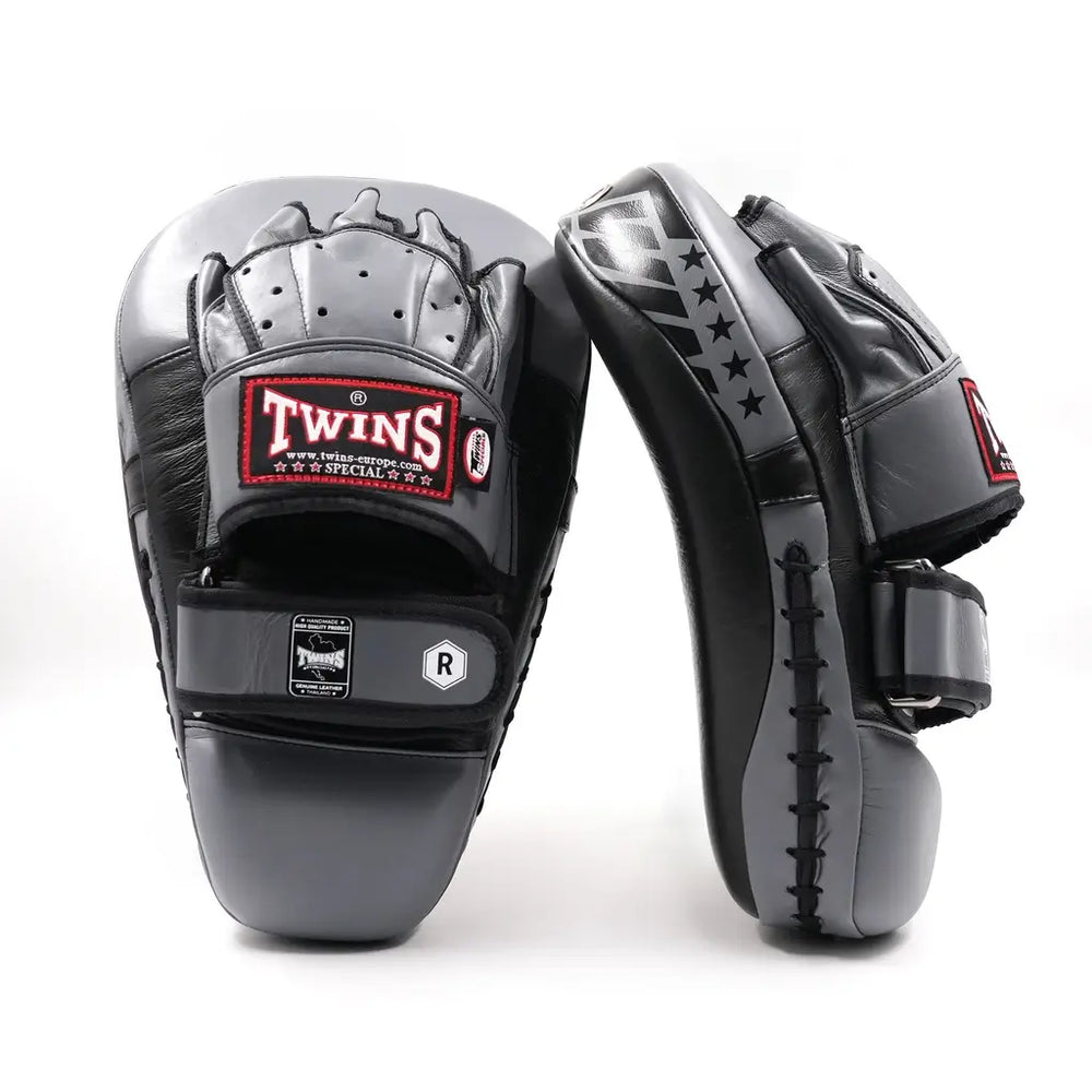 Zwarte en grijze Twins Special pads met handbescherming en klittenbandsluiting, voorzien van het Twins-logo en sterdetails, op een witte achtergrond.
