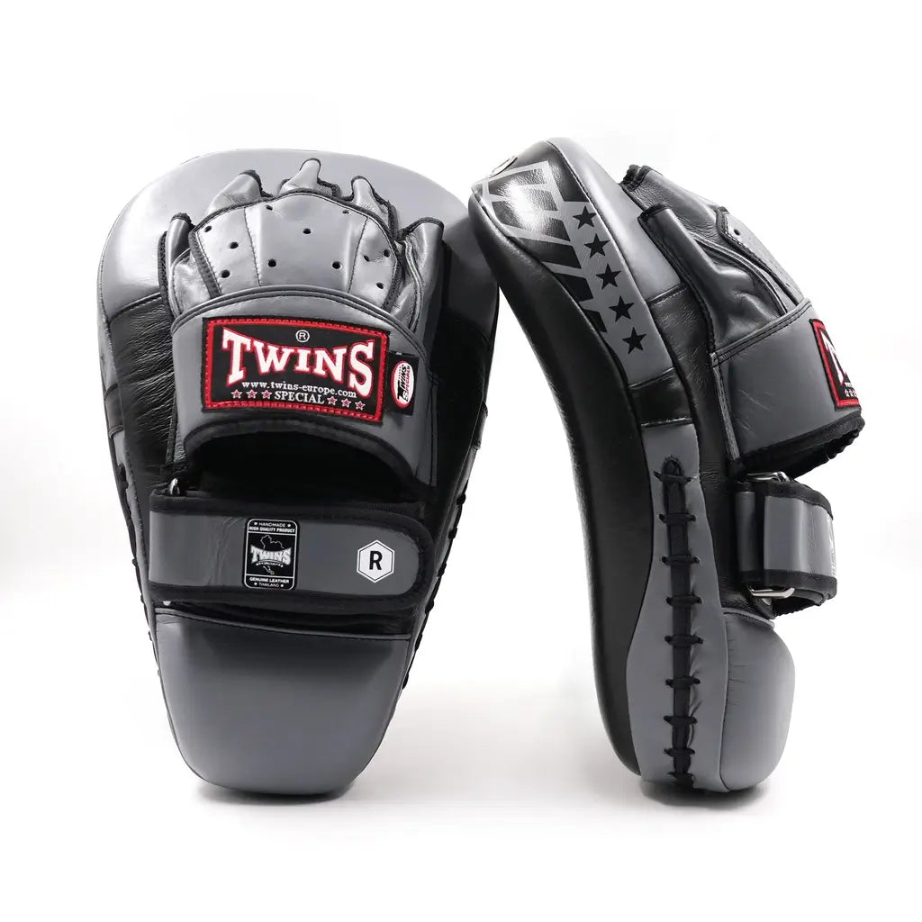 Zwarte en grijze Twins Special pads met handbescherming en klittenbandsluiting, voorzien van het Twins-logo en sterdetails, op een witte achtergrond.