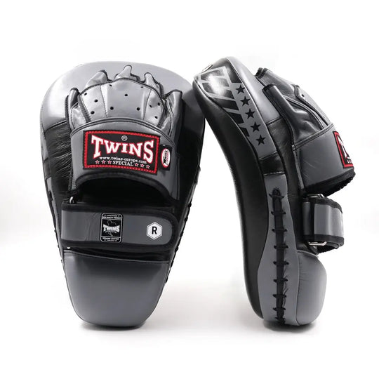 Zwarte en grijze Twins Special pads met handbescherming en klittenbandsluiting, voorzien van het Twins-logo en sterdetails, op een witte achtergrond.