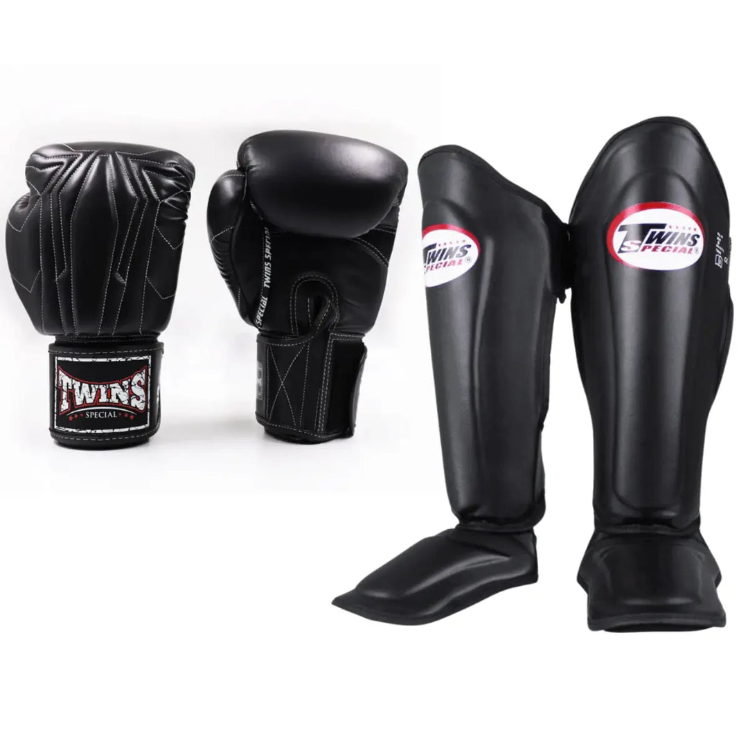 Twins Special set bestaande uit zwarte bokshandschoenen met witte stiksels en zwarte scheenbeschermers met logo, gepresenteerd tegen een witte achtergrond.
