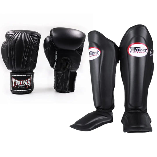 Twins Special set bestaande uit zwarte bokshandschoenen met witte stiksels en zwarte scheenbeschermers met logo, gepresenteerd tegen een witte achtergrond.