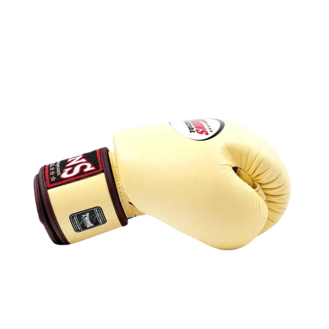 Twins Special Bokshandschoen Vanilla – Zijaanzicht van een premium leren bokshandschoen in elegante vanillekleur met donkerrode polsband en het klassieke Twins-logo. Biedt optimale demping, stevige polsondersteuning en een luxe afwerking voor intensieve bokstraining en sparring. Perfect voor boksers die stijl en prestaties willen combineren.