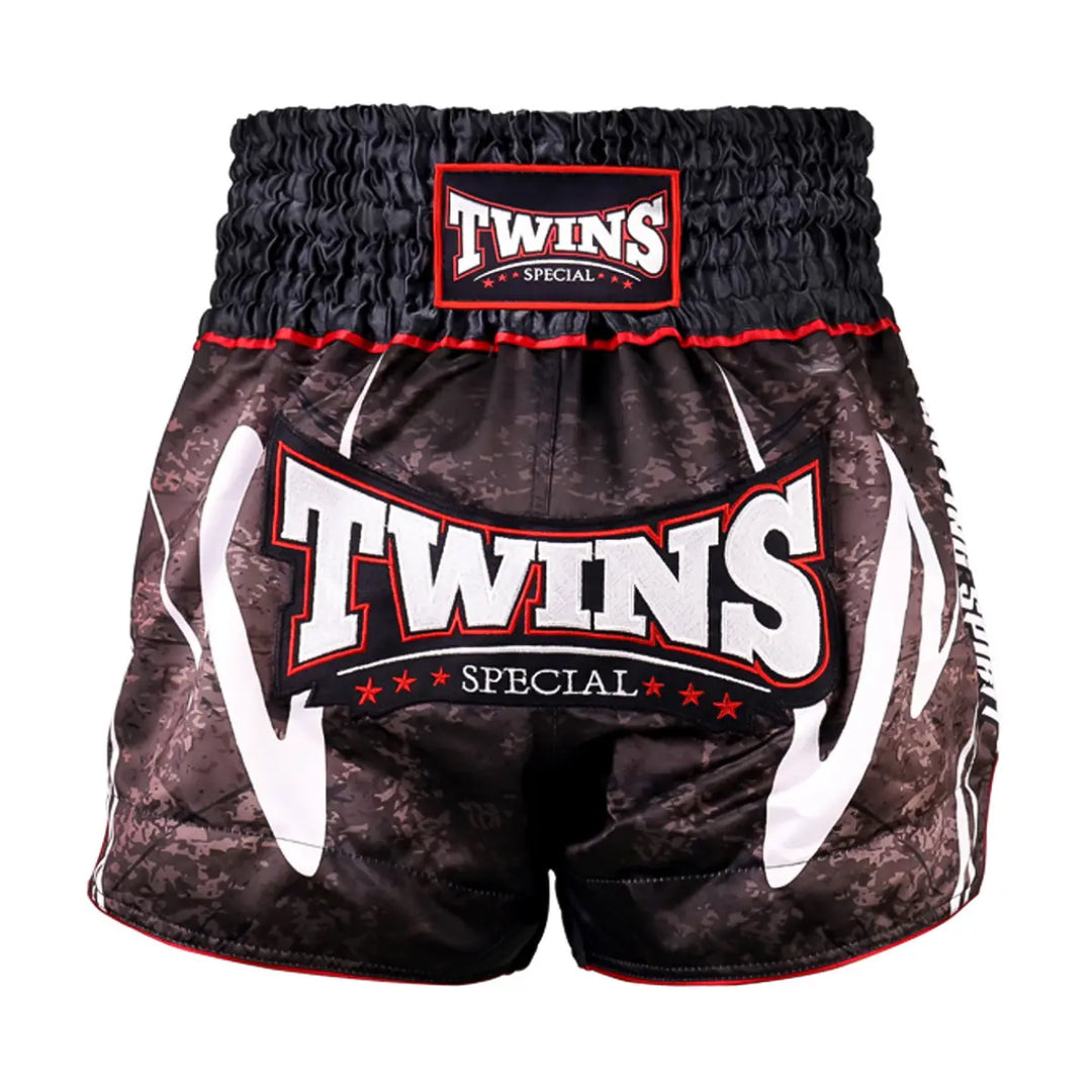 Twins Special TTBL kickboksbroekje in rusty black camouflage met groot Twins-logo op de voorzijde en brede elastische tailleband. Lichtgewicht short met hoge zijsplitten voor maximale bewegingsvrijheid tijdens intensieve kickbokstraining in de gym.