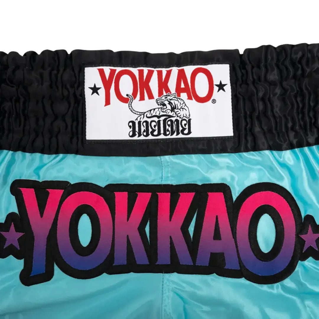 Taile van de YOKKAO Kickbox Broekje The Flame Tiffany. Het is zwart met de logo er duidelijk op. De logo is paars en roze. 