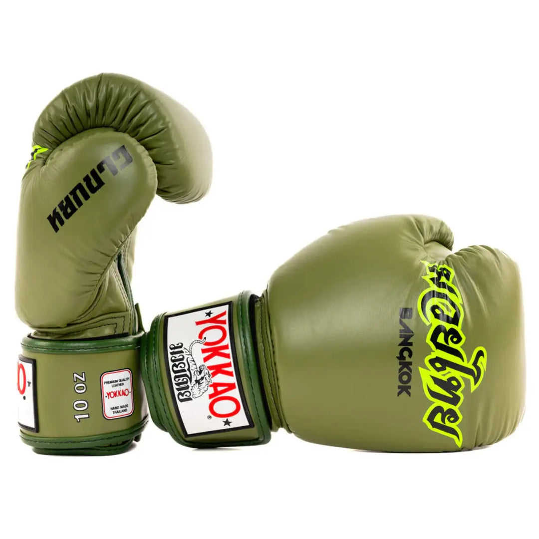 Yokkao Bokshandschoenen Bangkok Army Groen met zwarte en neongele details. Deze handgemaakte lederen handschoenen uit Thailand combineren duurzaamheid met uitstekende bescherming en pasvorm — perfect voor intensieve bokssessies en sparring.