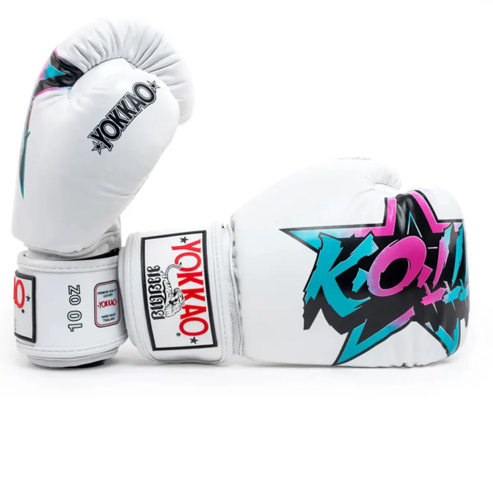 Yokkao Bokshandschoenen Fighter KO Wit met opvallende ‘KO!’-print in turquoise, roze en zwart. Handgemaakt van topkwaliteit leer in Thailand, met extra polsversteviging en duurzame padding voor optimale bescherming en comfort tijdens bokstrainingen.