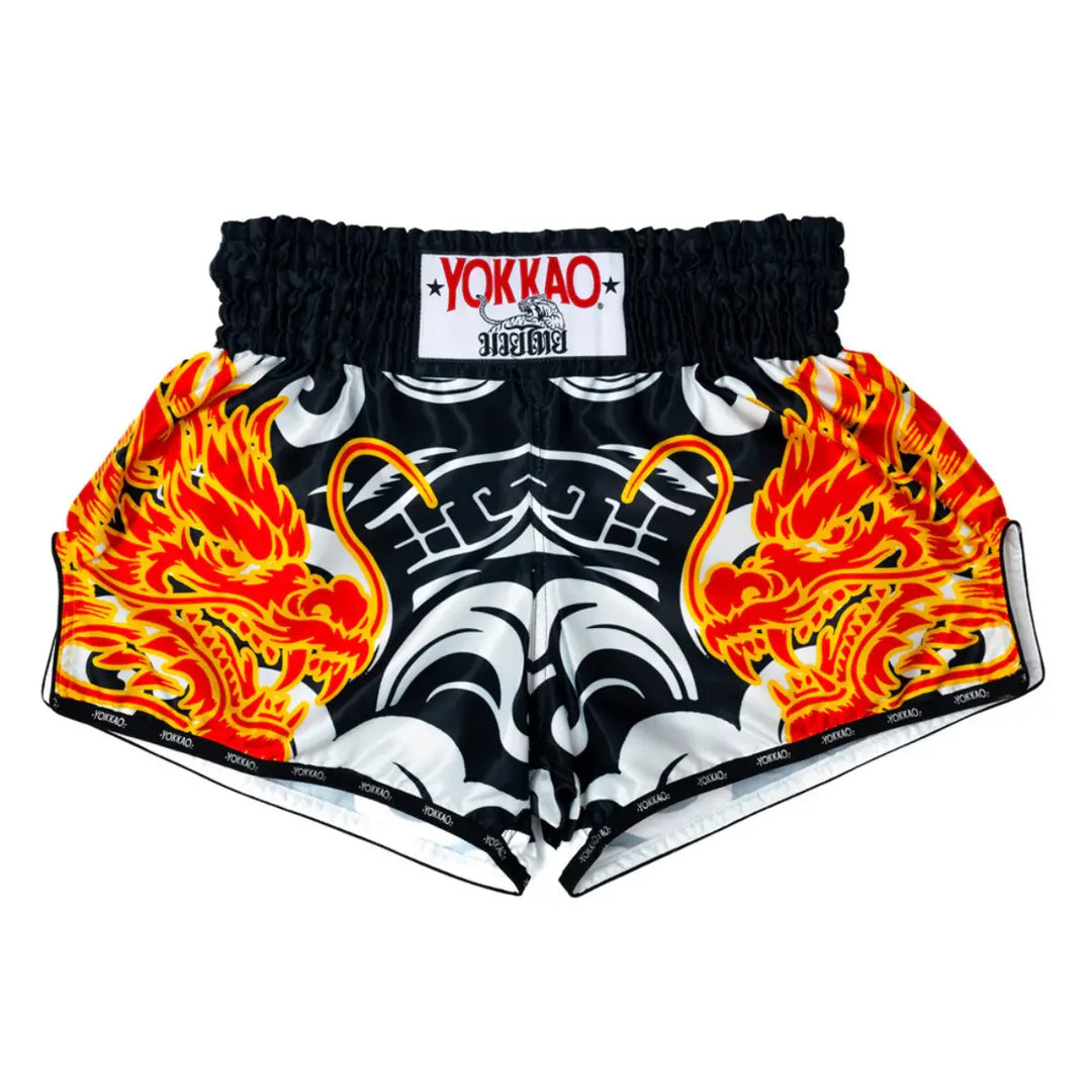Yokkao Kickboksbroek Dragon Inferno Zwart Wit met vurige drakenprints in rood en oranje aan de voorzijde. De satijnen stof biedt maximale bewegingsvrijheid en een luxueuze afwerking. Ontworpen voor kickboksers die kracht en stijl willen combineren tijdens training of competitie.