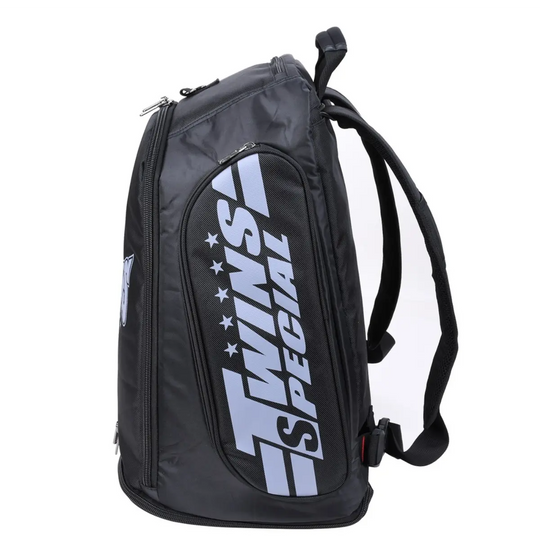 Zijaanzicht van de zwarte Twins Special rugtas met een groot, verticaal TWINS-logo in lichtblauw op het zijvak. Het stevige handvat en verstelbare schouderbanden maken deze tas ideaal voor intensief gebruik door boksers en kickboksers. Ontworpen voor zowel stijl als functionaliteit.