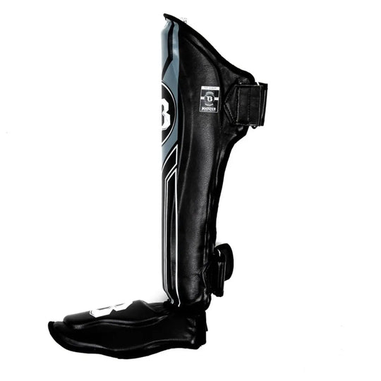 Zijaanzicht van een Booster BGL V9 scheenbeschermer in de kleur zwart met donkergrijze accenten. De afbeelding toont de been- en voetbescherming met de klittenbandsluitingen