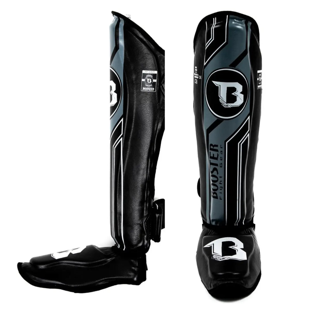 Paar Booster BGL V9 scheenbeschermers (kickboksen/muay thai) in de kleur zwart met donkergrijze/antraciete accenten en witte contourlijnen. Getoond: zijaanzicht en voorkant.

