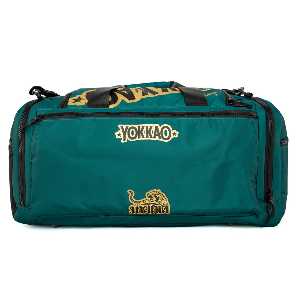 Yokkao sporttas in groen met goudkleurig YOKKAO-logo en Muay Thai-embleem op de achterzijde. De tas heeft stevige zwarte handgrepen bovenop, meerdere ritsvakken en robuuste ritssluitingen aan de zijkanten. Ideaal als ruime gymtas voor boksen, Muay Thai en dagelijkse trainingssessies.