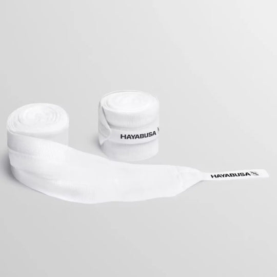 Een paar opgerolde witte Hayabusa handwraps, waarvan één gedeeltelijk afgerold is om de manchet met het zwarte Hayabusa-logo te tonen.
