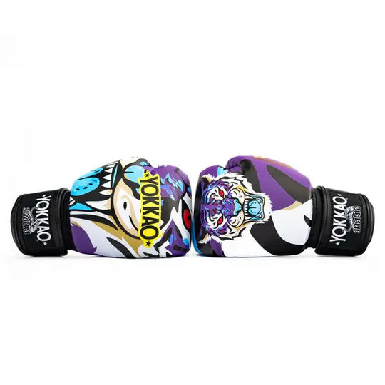 Twee Yokkao Angry Tiger bokshandschoenen liggend tegenover elkaar tegen een witte achtergrond. De paarse handschoenen tonen de kleurrijke tijgerprint met blauwe en witte accenten en het gele YOKKAO-logo op de voorkant. De zwarte klittenbandsluiting met merklogo is zichtbaar aan beide zijden.