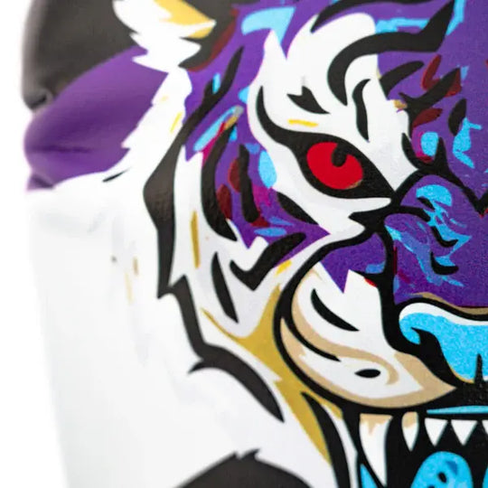 Extreme close-up van de Yokkao Angry Tiger bokshandschoen met focus op het rode tijgeroog en de paarse, blauwe en witte illustratie. De scherpe zwarte lijnen en contrasterende kleuren benadrukken het agressieve design. De print is duidelijk zichtbaar tegen de paarse en witte panelen van de handschoen.