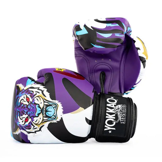 Twee Yokkao Angry Tiger bokshandschoenen gepositioneerd tegen een witte achtergrond, waarbij zowel de voorkant als de achterkant zichtbaar is. De paarse handschoenen hebben een opvallende tijgerillustratie met rode ogen en blauwe accenten. De zwarte klittenbandsluiting toont het Yokkao-logo in wit voor een herkenbare afwerking.