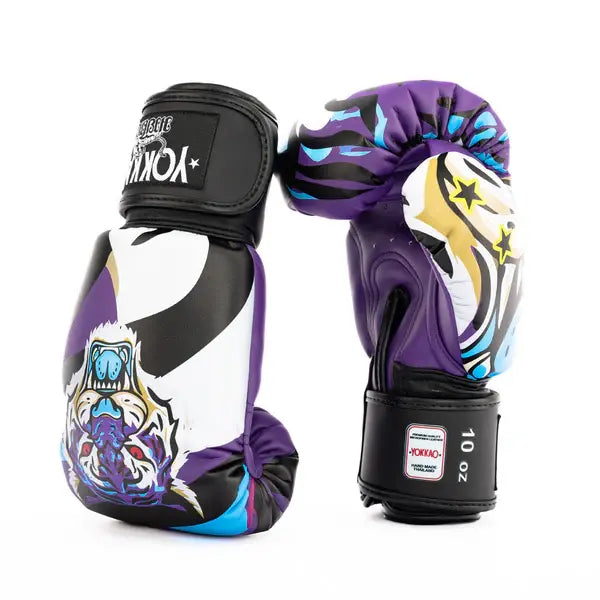 Set Yokkao Angry Tiger bokshandschoenen in paars met kleurrijke tijgerprint, gefotografeerd tegen een witte achtergrond. Eén handschoen toont de voorkant met tijgerillustratie, de andere de achterkant met zwarte klittenbandsluiting en 10 oz label. Het ontwerp combineert paars, zwart, wit en blauwe accenten voor een opvallende uitstraling.