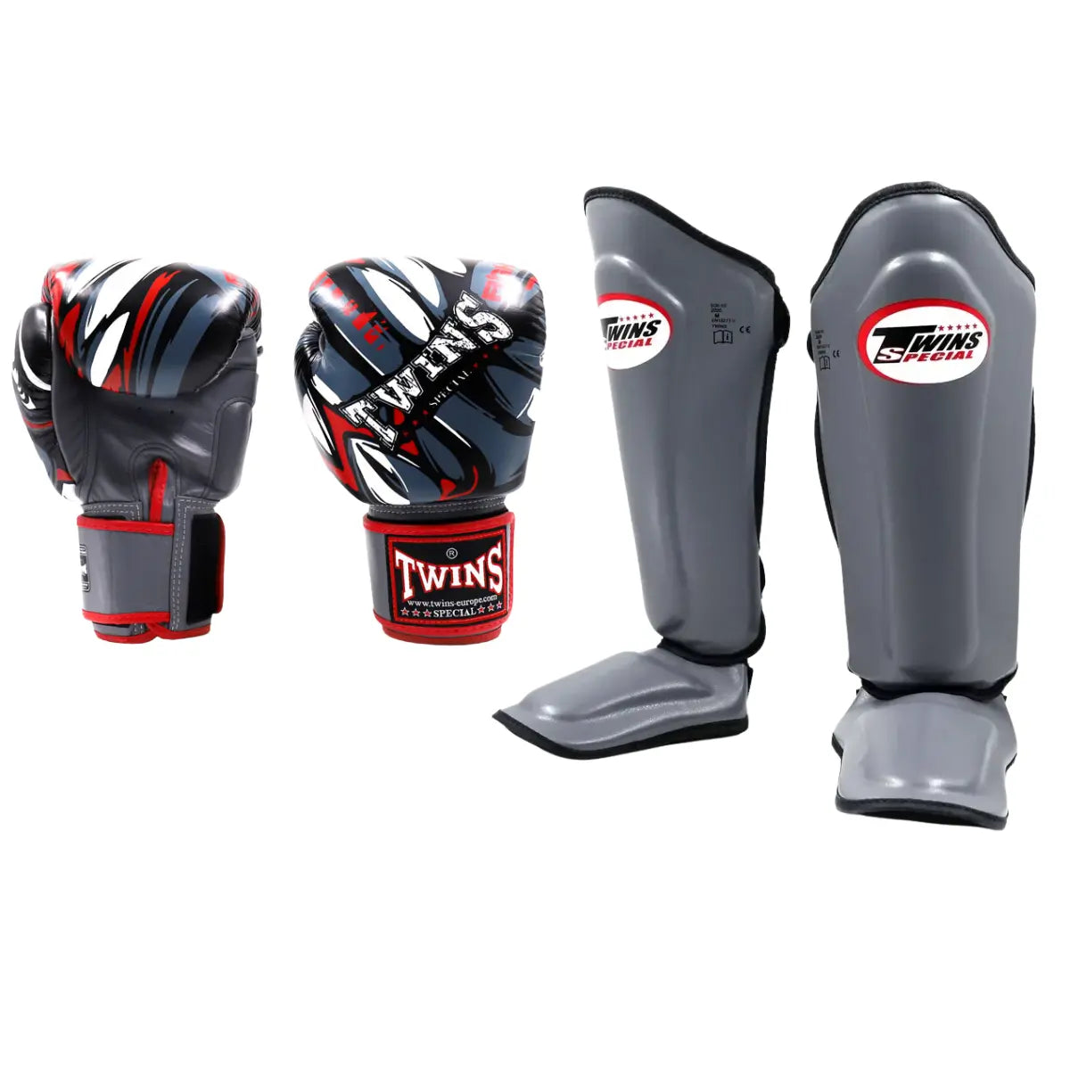 Twins Special FBGVL3 Demon set bestaande uit bokshandschoenen met zwart, grijs en rood design en bijpassende grijze SGL7 scheenbeschermers. Voorzien van stevige padding, brede polsband en geïntegreerde voetbescherming voor optimale bescherming tijdens boksen en kickbokstraining in de gym.