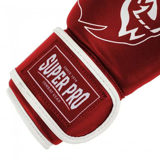 Close-up van rode kinder kickbokshandschoen met witte bies en Super Pro logo op klittenbandsluiting.
