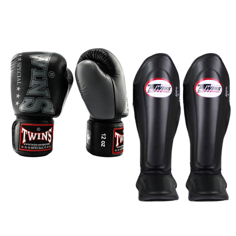 Twins Special kickboksset BGVL-8 in de kleur matzwart/antraciet. De set bestaat uit een paar bokshandschoenen (12oz) en een paar bijpassende scheenbeschermers met rode logo's
