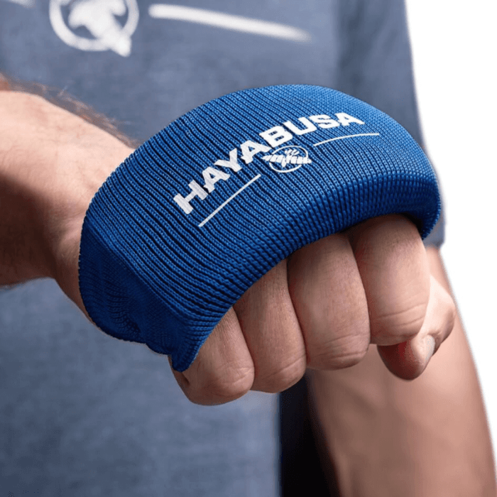 Een Hayabusa Boxing Knuckle Guard gedragen om de knokkels van een gebalde vuist, met het logo en adelaarsembleem zichtbaar bovenop de hand.