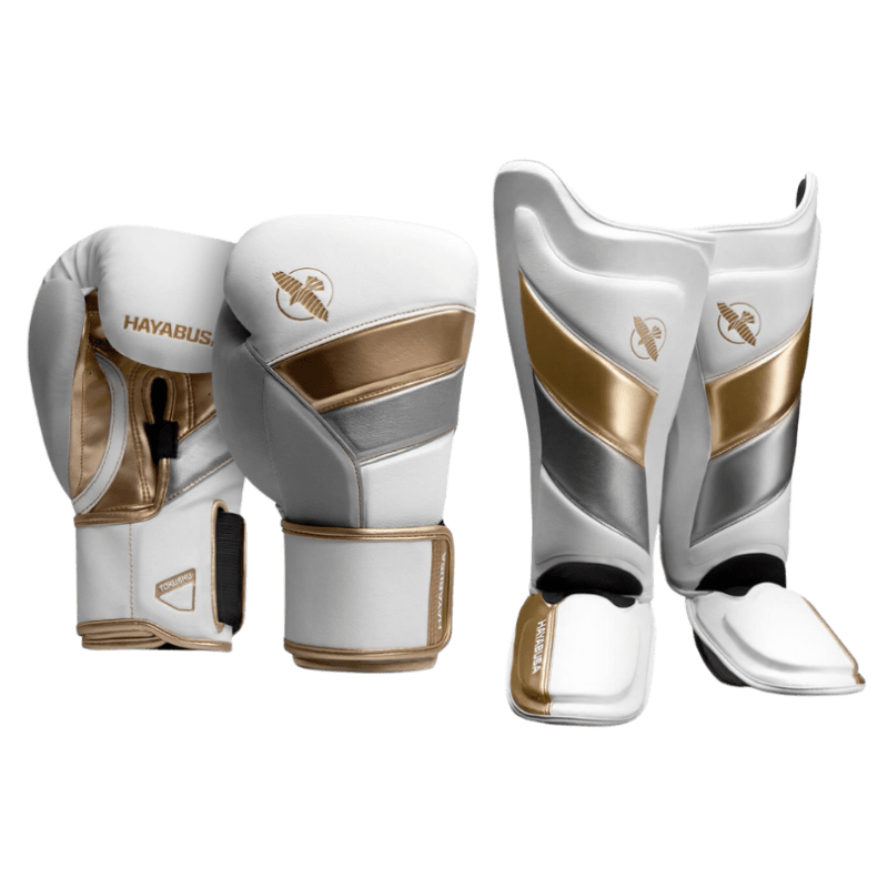 Een paar witte en gouden Hayabusa bokshandschoenen en scheenbeschermers, gericht op gevechtssport.