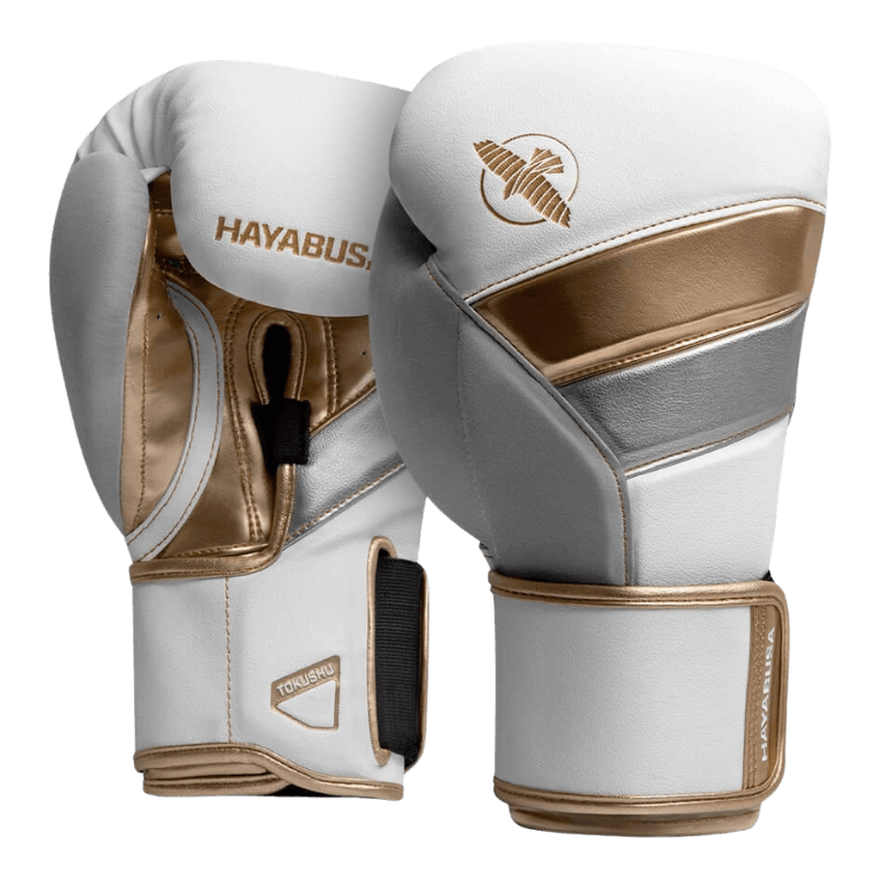 Een paar Hayabusa T3 bokshandschoenen in wit met gouden en zilveren details, zichtbaar vanaf de voorkant met de gouden Hayabusa-valk en merknaam op de rug van de handschoenen.