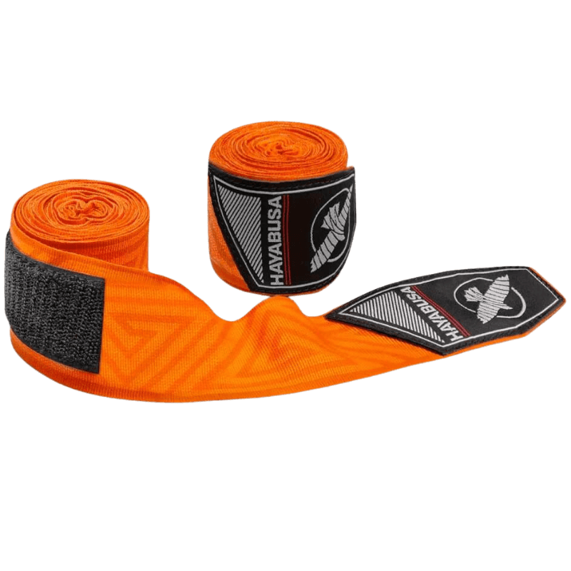 De oranje Hayabusa Perfect Stretch Bandages gedeeltelijk uitgerold, met het doolhofpatroon zichtbaar over de gehele lengte en het Hayabusa valk-logo op de bandagesluiting.