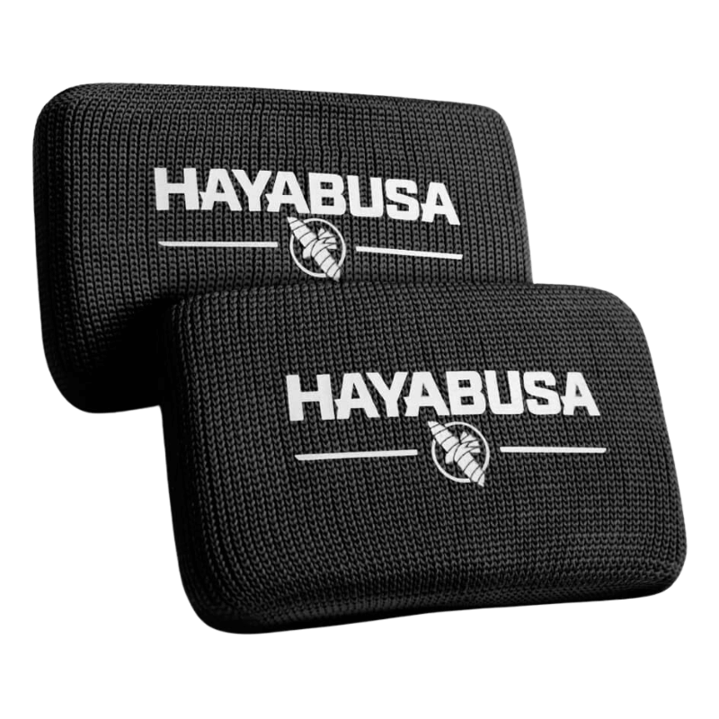 Twee zwarte Hayabusa Boxing Knuckle Guards met het Hayabusa-logo en het adelaarsembleem in wit, gestapeld op een donkere achtergrond.